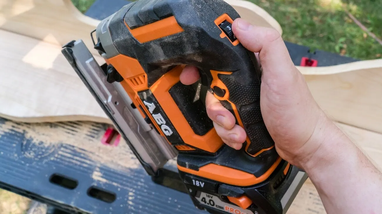 Stichsäge von AEG in orange-schwarz, Daumen verstellt die Stufen an der Stichsäge.