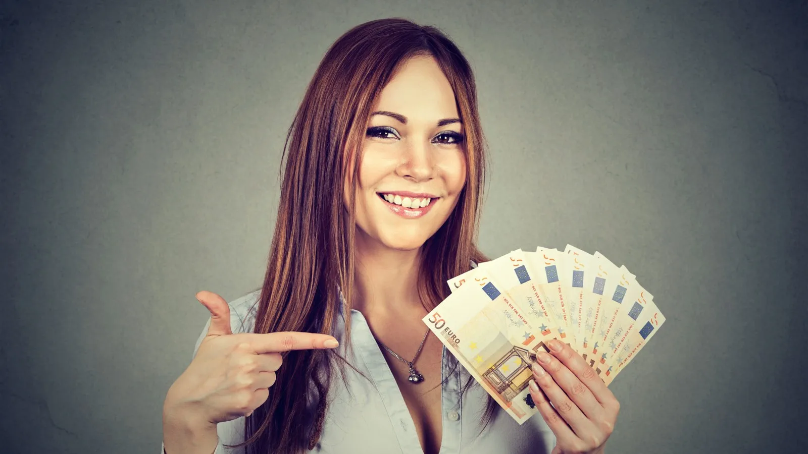 Eine Frau hält mehrere 50 Euro Scheine in der Hand und zeigt mit dem Finger darauf.