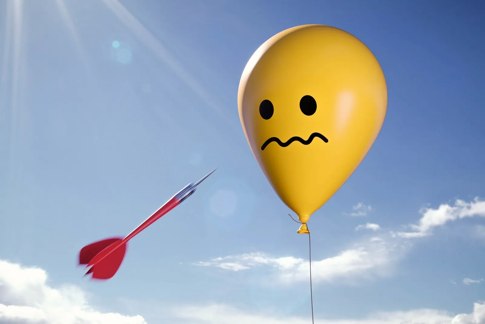 Ein gelber Luftballon mit einem verunsichertem Smiley am Himmel. Ein roter Dartpfeil fliegt auf den Ballon zu.