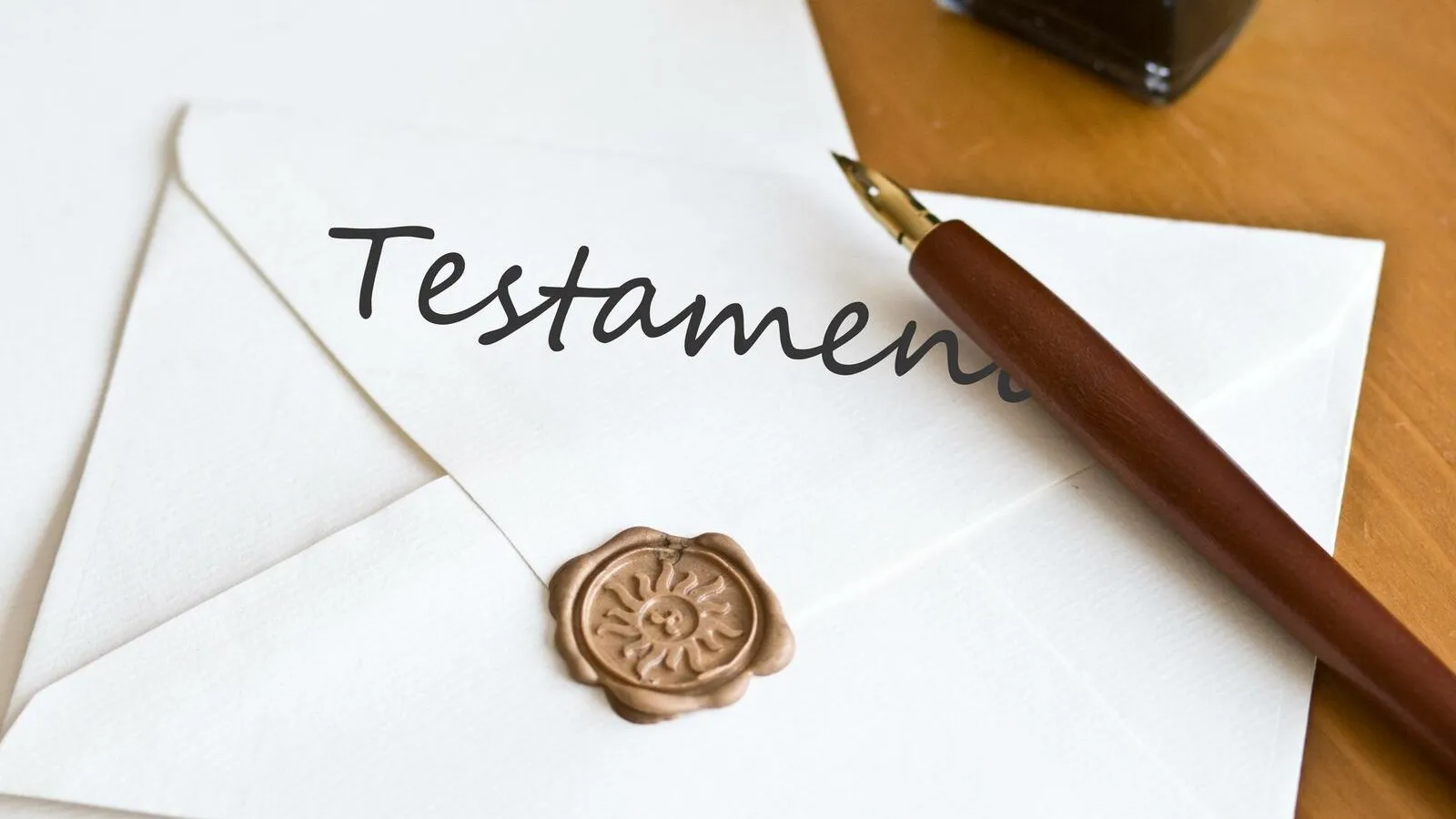 Ein Briefumschlag mit einem goldenen Wachssiegel und der Aufschrift "Testament". Darauf liegt ein Stift.