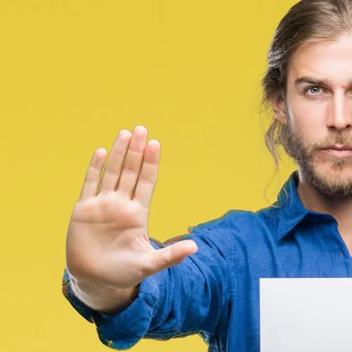  Mann steht vor einem gelben Hintergrund und hat ein Blatt papier in der Hand – mit der anderen Hand gestikuliert er "Stop"