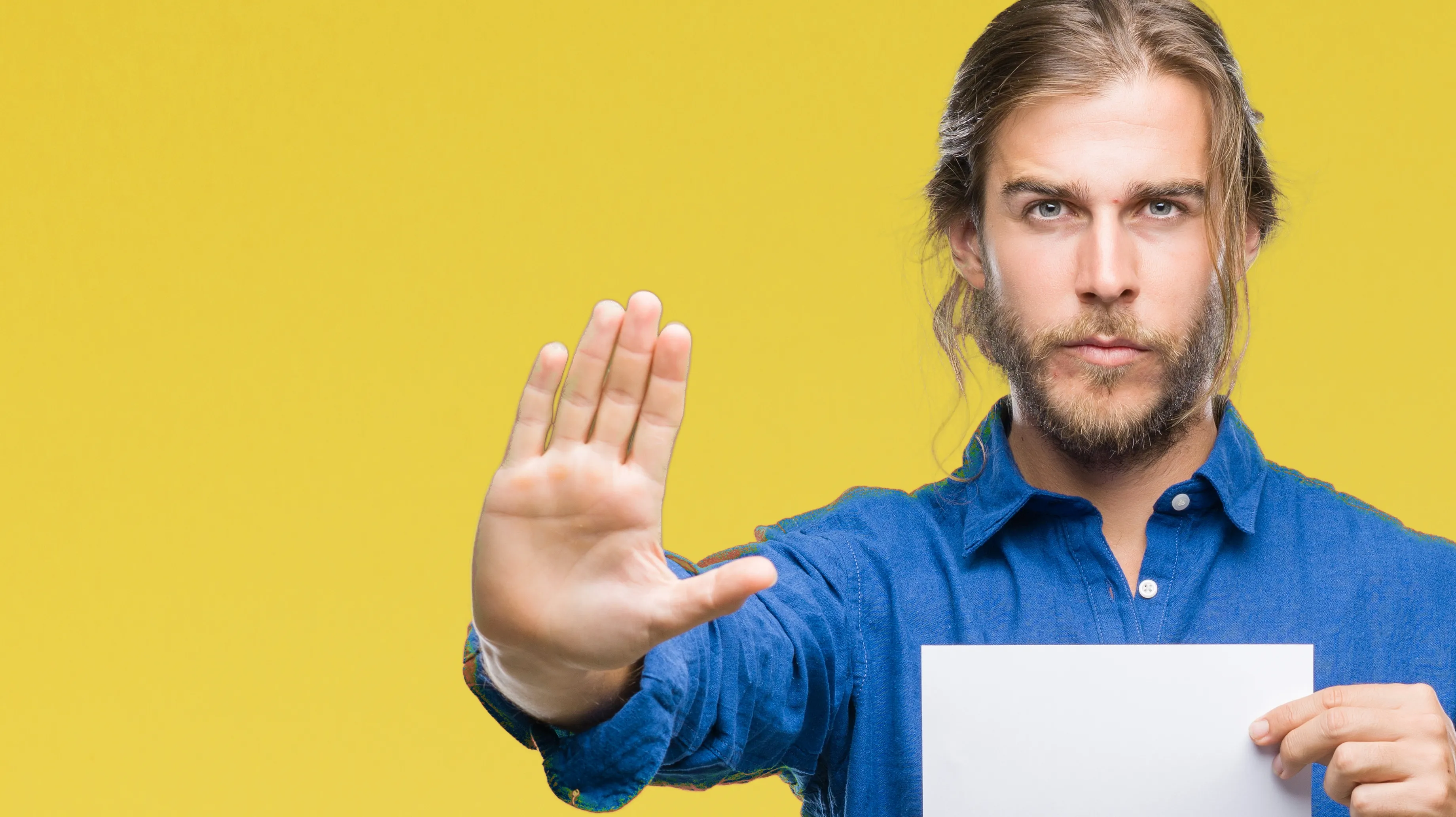  Mann steht vor einem gelben Hintergrund und hat ein Blatt papier in der Hand – mit der anderen Hand gestikuliert er "Stop"