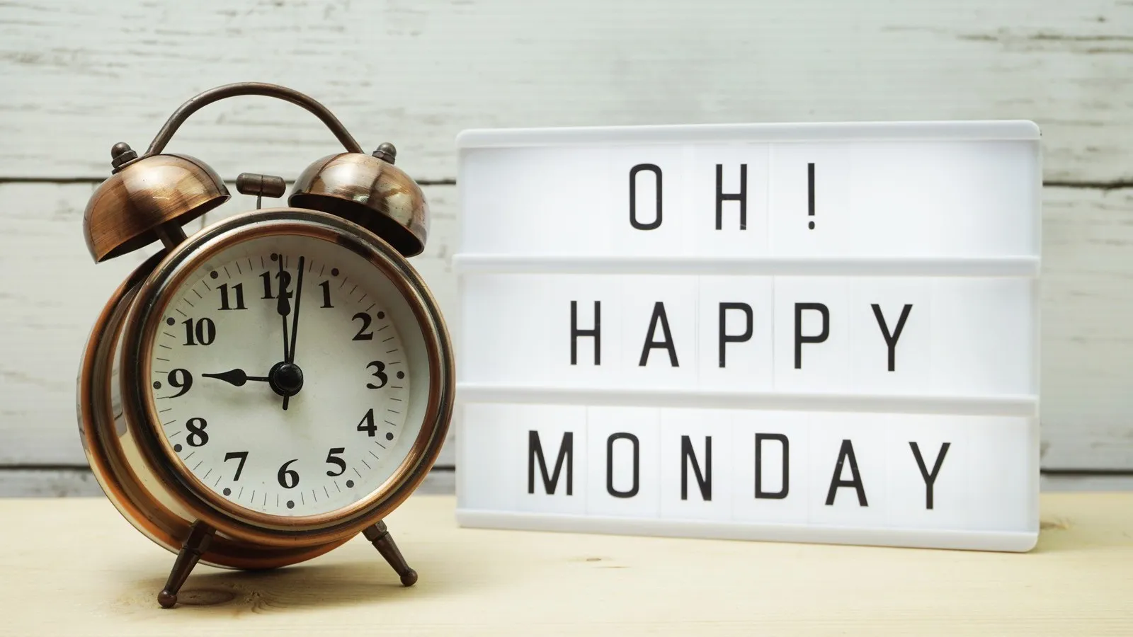 Ein Wecker steht neben einer weißen Lightbox mit der Aufschrift "OH! HAPPY MONDAY".