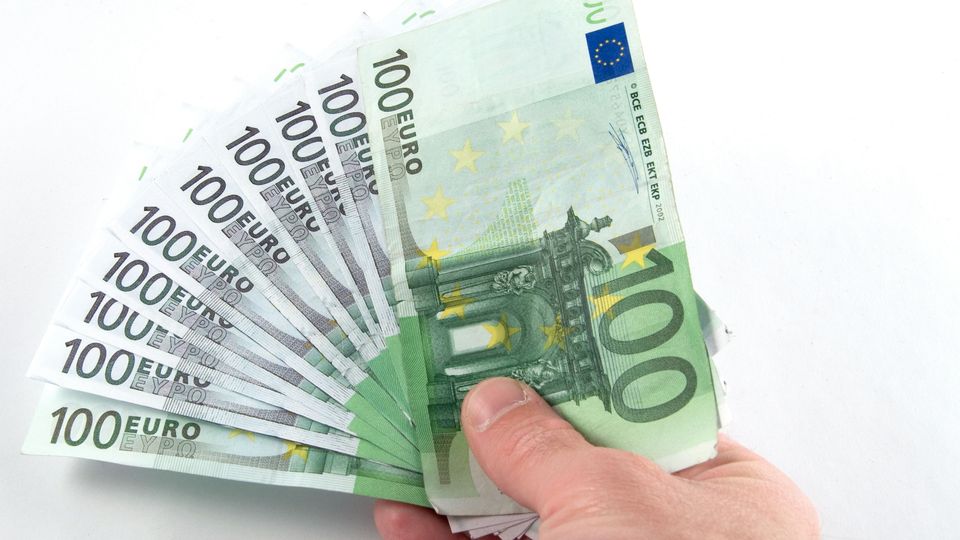 Jemand hält 10 Geldscheine in der Hand – insgesamt sind es 1000 Euro.