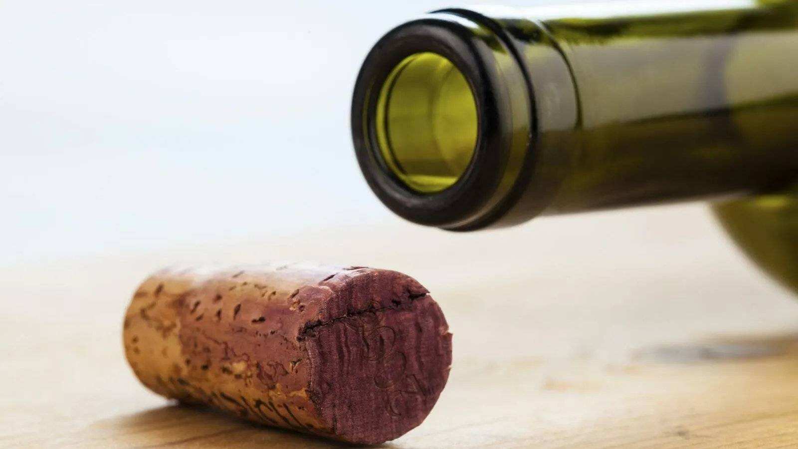Nahaufnahme der Öffnung einer Champagner oder Sekt Flasche, davor liegt der Korken.