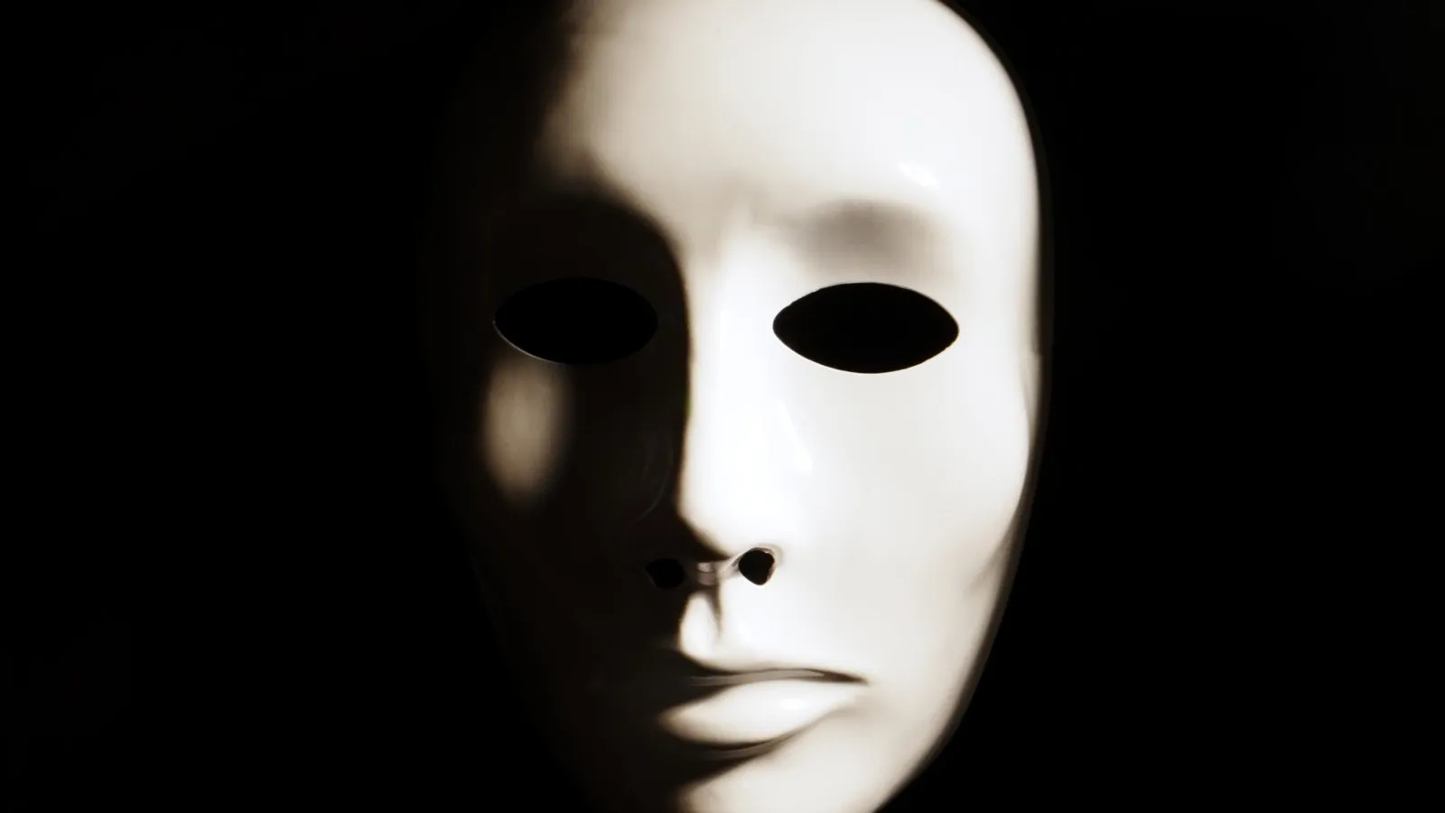 Eine weiße "anonym" Maske vor einem dunklen Hintergrund.