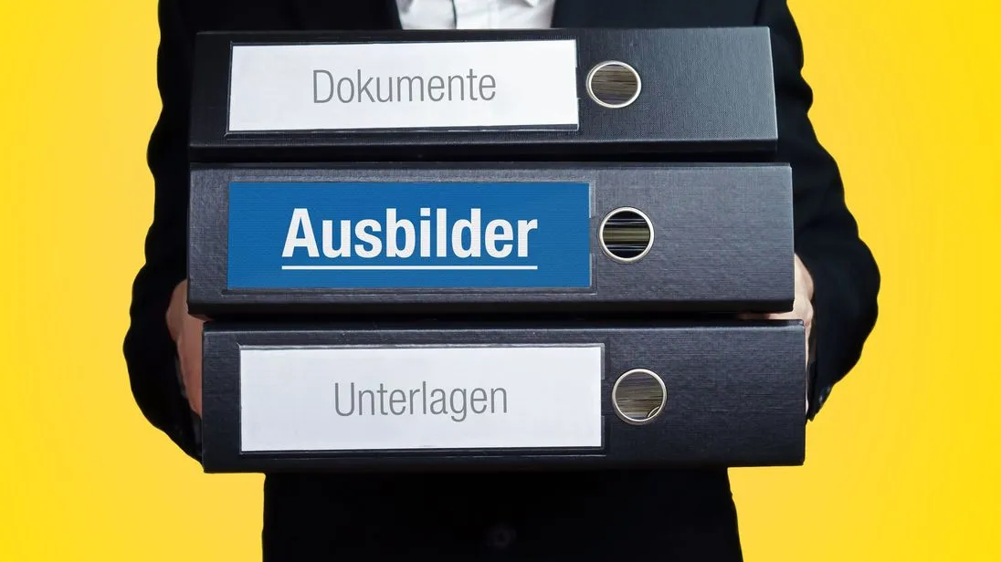Ein Ausbilder trägt drei Ordner. SIe sind mit folgenden Wörtern beschriftet: Dokumente, Ausbilder, Unterlagen.