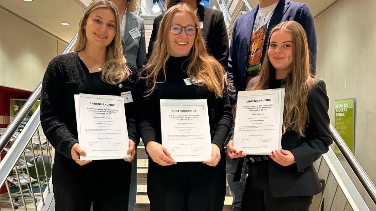Die Bestatterinnen Katharina Neusiedler, Mona May Hansen und Sonja Tönsing (v. l. n. r.) stehen für ein gemeinsames Foto nebeneinander mit ihren Auszeichnungen in den Händen.
