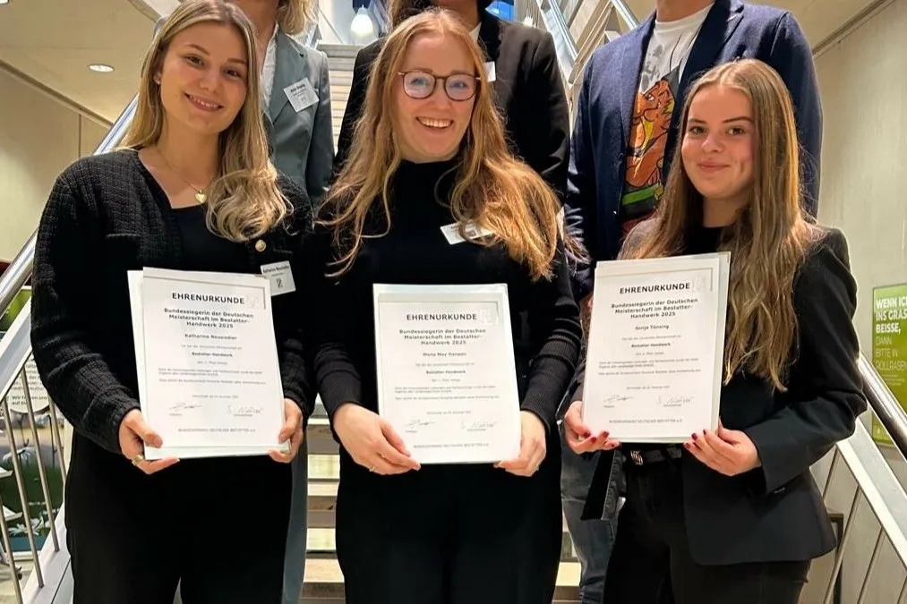 Die Bestatterinnen Katharina Neusiedler, Mona May Hansen und Sonja Tönsing (v. l. n. r.) stehen für ein gemeinsames Foto nebeneinander mit ihren Auszeichnungen in den Händen.