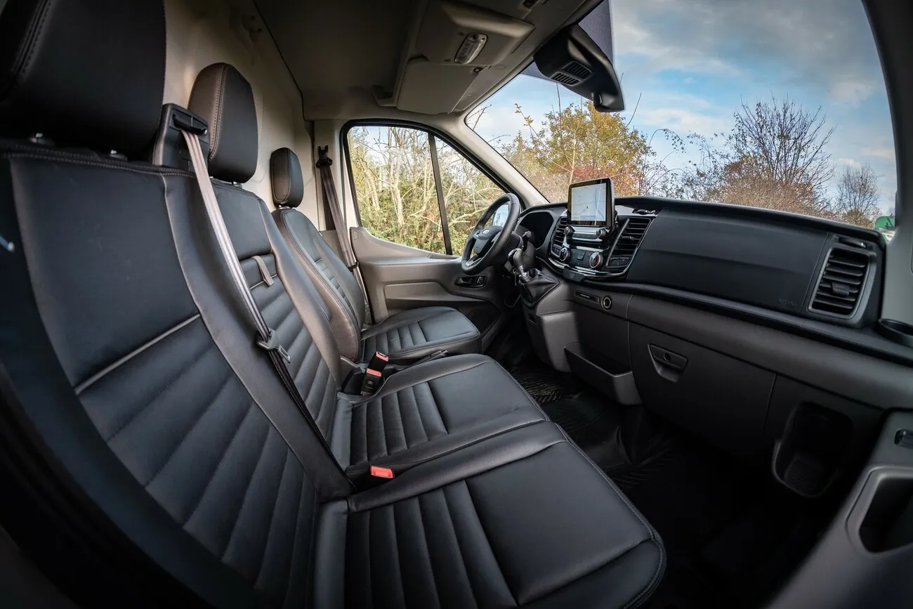 Sitzbank im Inneren des Ford Transit Trail 4x4 mit schwarzen Kunstledersitzen.