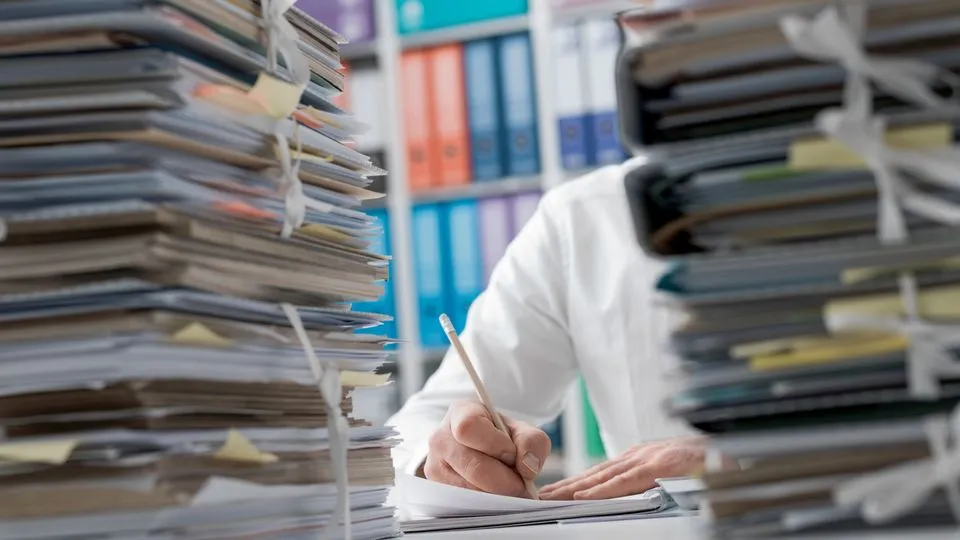 Unterlagen stapeln sich auf dem Schreibtisch eines Unternehmers