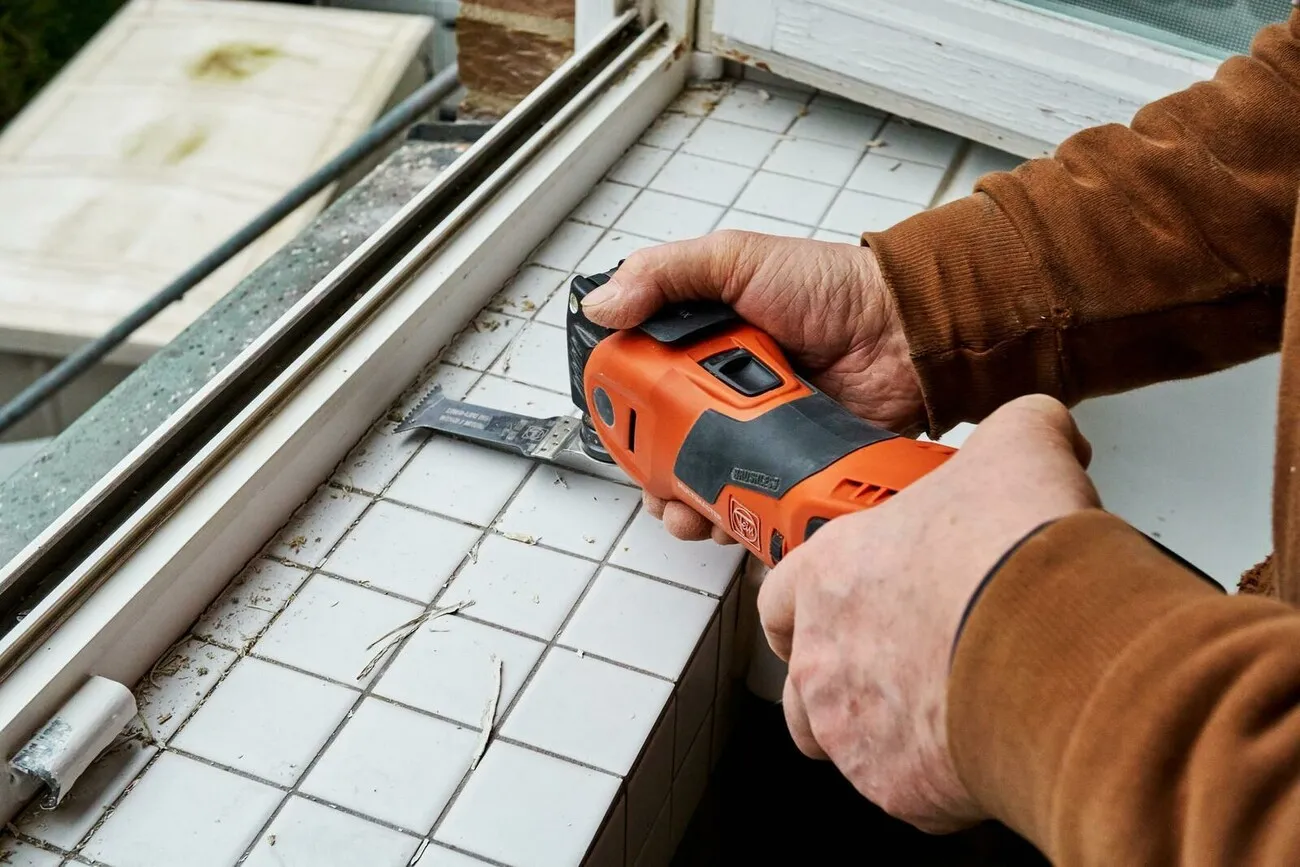 Ein Handwerker arbeitet mit dem Fein Multimaster 700 an der Innenseite eines Fensters.