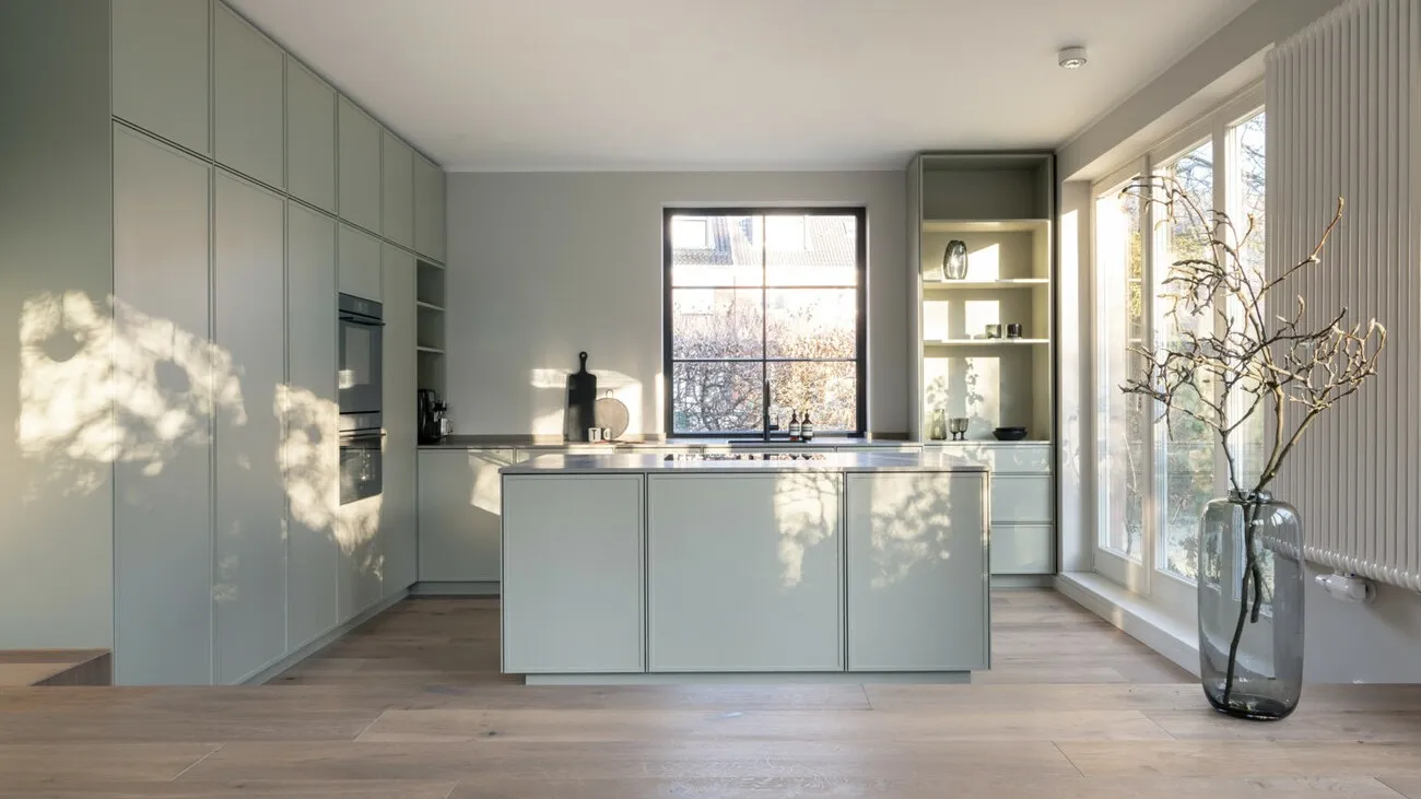 Eine reale moderne Küche in weißem Hochglanz mit einem sechsgeteilten Fenster in der Mitte.