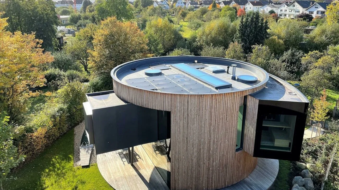 Ein Drehhaus mit Holzoptik und schwarzen großen Fenstern.