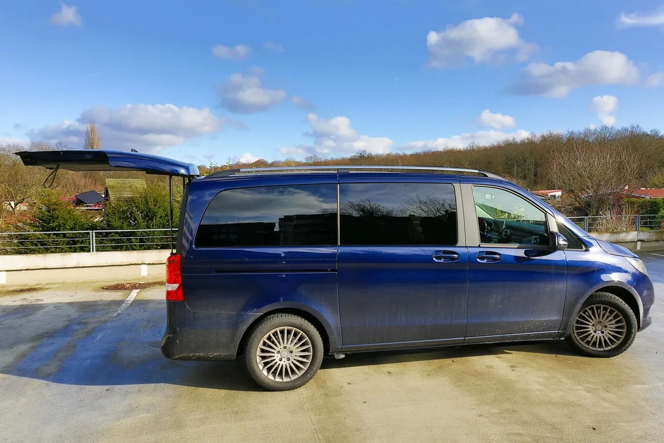 Die Mercedes V Klasse in dunkelblau von der Seite, auf einem verlassenen Parkplatz.