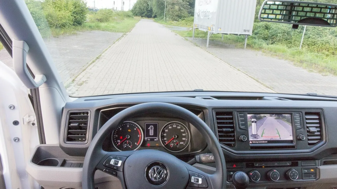 Innenperspektive aus der Sicht des Fahrers mit Blick aufs Cockpit und einen Weg vor dem Fahrzeug.