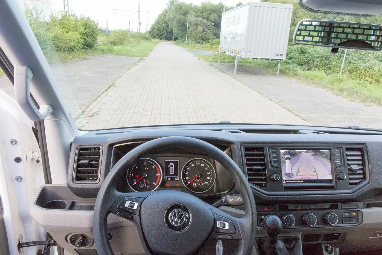 Innenperspektive aus der Sicht des Fahrers mit Blick aufs Cockpit und einen Weg vor dem Fahrzeug.