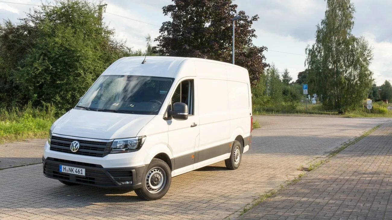 Der weiße VW Crafter in einer seitlichen Frontansicht auf einem Weg stehend.