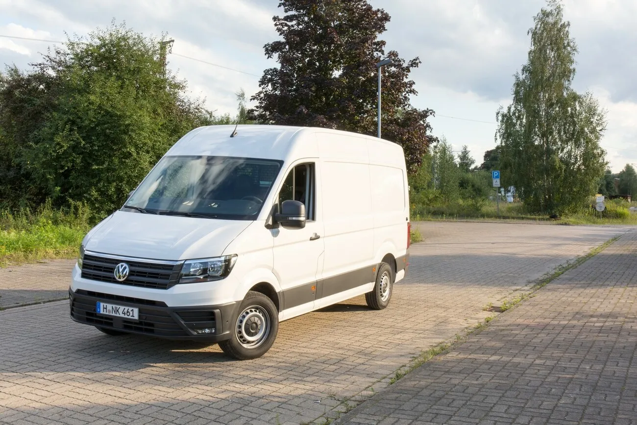 Der weiße VW Crafter in einer seitlichen Frontansicht auf einem Weg stehend.
