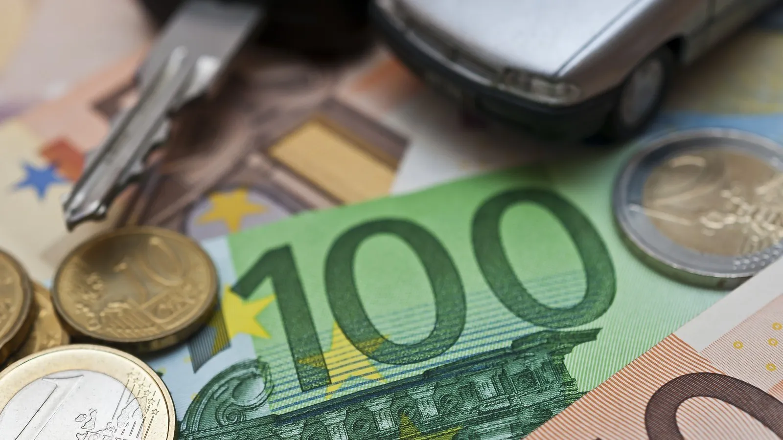 Neben einem Autoschlüssel liegen ein 100 Euro und ein 50 Euro Schein sowieso einige Münzen.