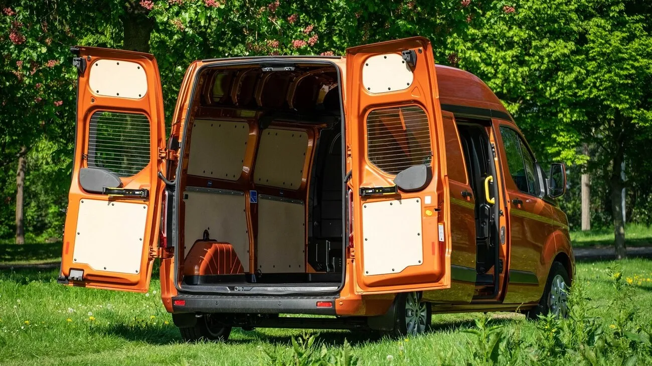 Der orangene Ford Transit Custom wird von hinten gezeigt mit geöffnetem Kofferraum und Blick ins Innere.