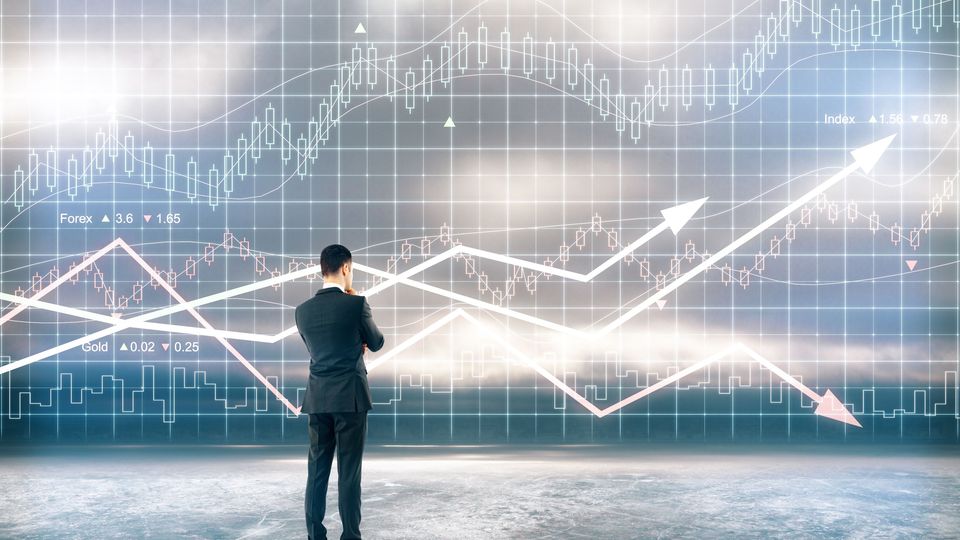 Ein Mann im Anzug betrachtet einen Candlestick-Chart, mit denen Kursverläufe von Aktien visualisiert werden.