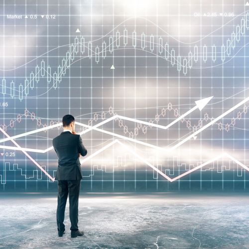 Ein Mann im Anzug betrachtet einen Candlestick-Chart, mit denen Kursverläufe von Aktien visualisiert werden.