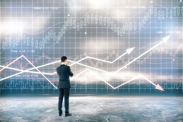Ein Mann im Anzug betrachtet einen Candlestick-Chart, mit denen Kursverläufe von Aktien visualisiert werden.
