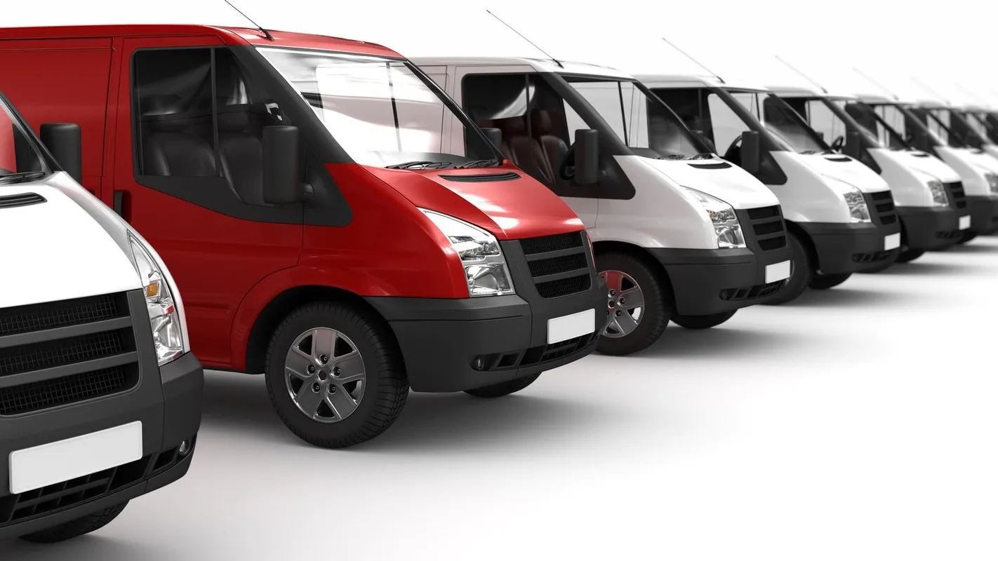 Ein roter Transporter parkt neben einer Reihe von weißen Transportern.