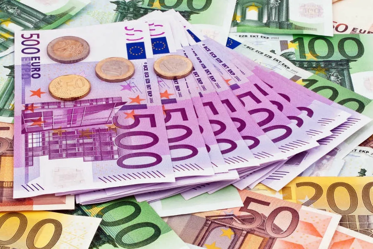 Viele Euro-Geldscheine mit mehreren 500 Euro Scheinen in der Mitte und darauf ein paar Münzen.