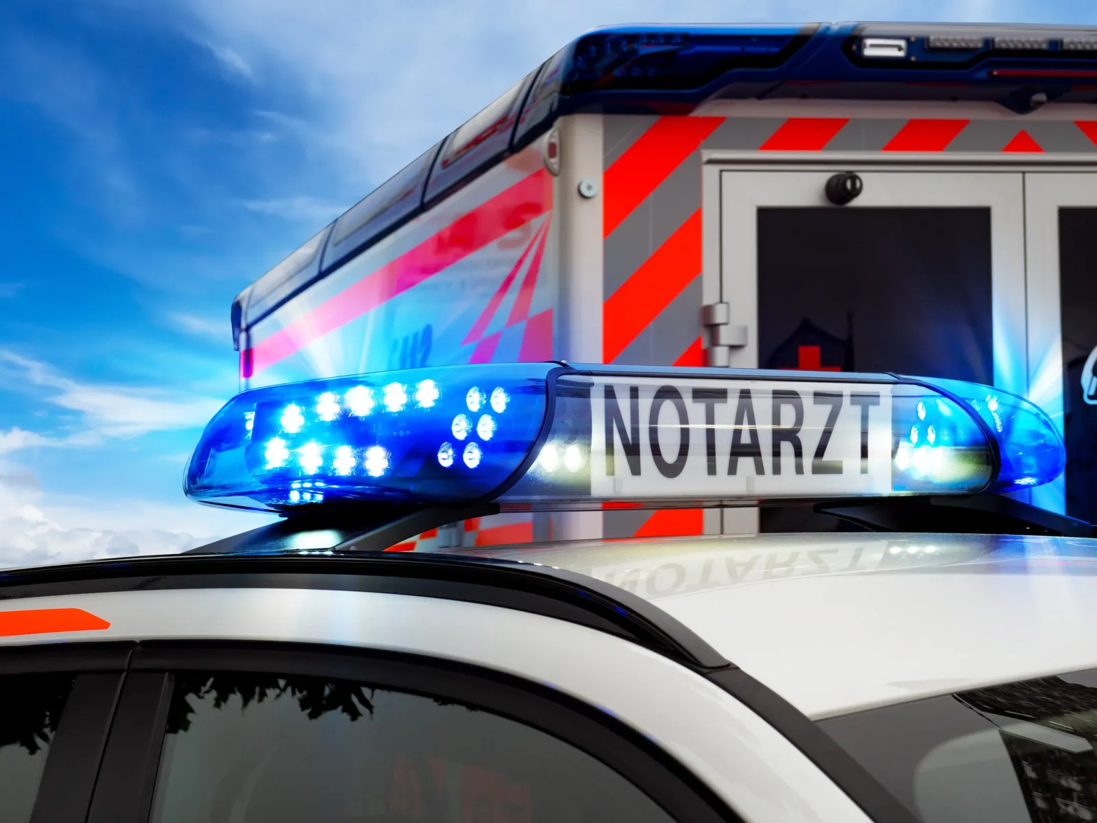 Nahaufnahme des Blaulichts eines Notarztfahrzeugs. Im Hintergrund steht ein Rettungswagen.