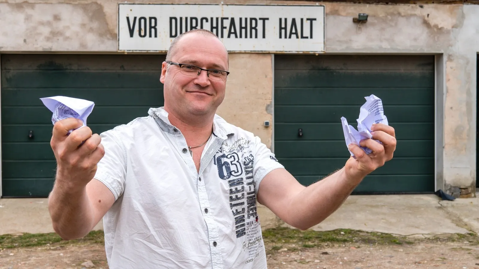 Foto von Martin Heinrich mit zerknülltem Papier in den Händen, vor einer Durchfahrt stehend.