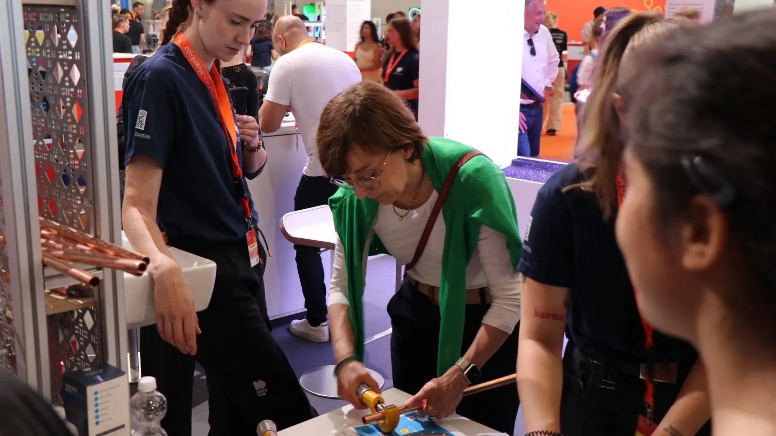 Sandra Hunke, Content Creatorin und gelernte Anlagenmechanikerin im Bereich Sanitär, Heizung und Klima, unterstützt Staatssekretärin Christine Arbogast beim Ablängen eines Kupferrohrs.