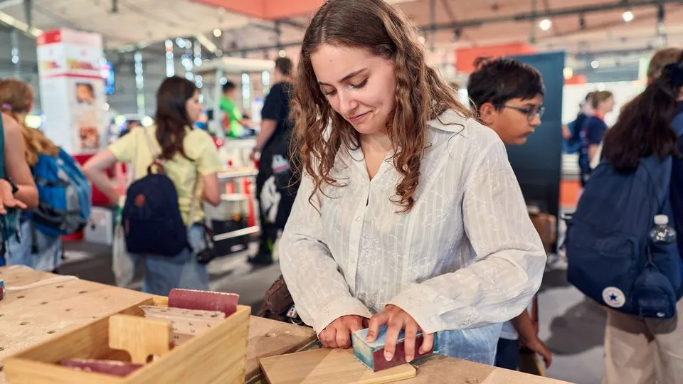 Mädchen probiert die Arbeit mit Holz auf der Ideenexpo
