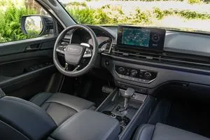 Der Innenraum des KGM Musso mit Lenkrad, Display und Ledersitzen.