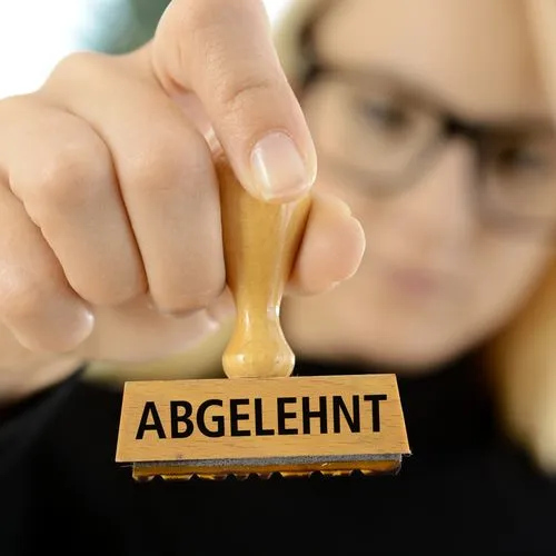 Eine Frau hält einen Stempel mit der Aufschrift "abgelehnt" in der Hand.