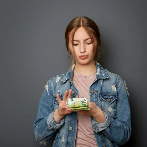 Eine Schülerin in Jeansjacke zählt ein Bündel Geldscheine. Dabei spitzt sie stolz die Lippen.