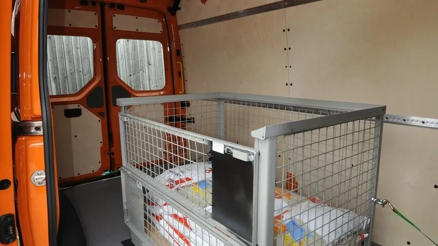 Innenansicht: Nähere Aufnahme des Innenraums des MAN TGE mit einer Metallgitterbox beladen.