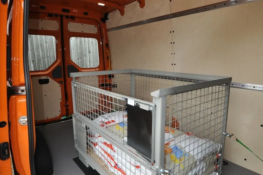 Innenansicht: Nähere Aufnahme des Innenraums des MAN TGE mit einer Metallgitterbox beladen.