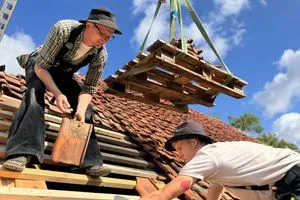 Hier verlegen Azubi und Meister die alten Ziegel wieder fachgerecht auf dem Dach des denkmalgeschützten Hauses.
