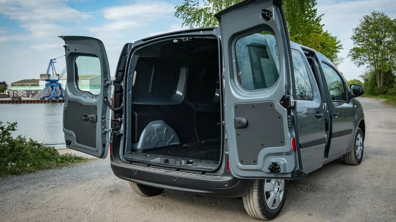 Der grau-schwarze Nissan NV250 seitlich von hinten, mit geöffneten Hecktüren.