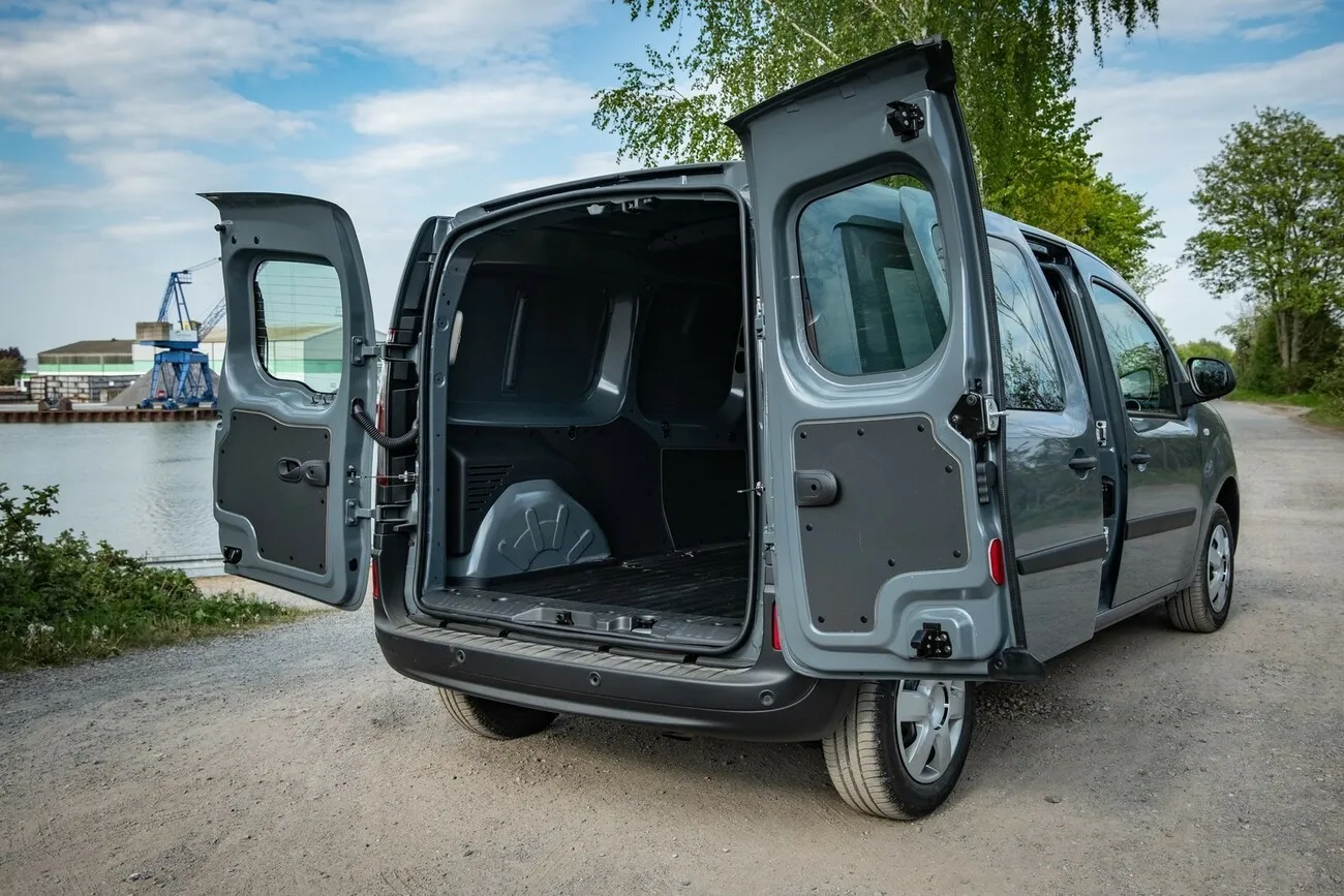 Der grau-schwarze Nissan NV250 seitlich von hinten, mit geöffneten Hecktüren.