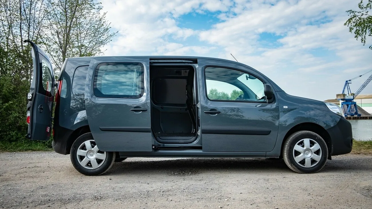 Der grau-schwarze Nissan NV250 von der Seite (Beifahrerseite) mit geöffneter hinterer Schiebetür.