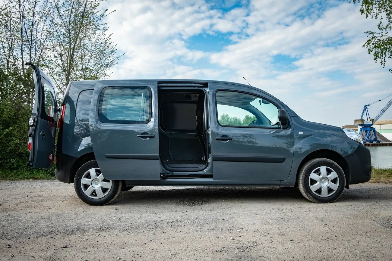 Der grau-schwarze Nissan NV250 von der Seite (Beifahrerseite) mit geöffneter hinterer Schiebetür.