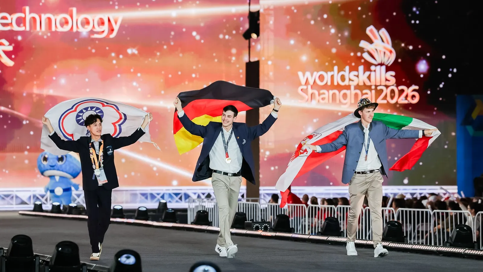 Der frischgebackene Weltmeister Tobias Kelz schreitet zwischen seinen Mitstreitern der Disziplin „Möbelschreiner“ über die Bühne.