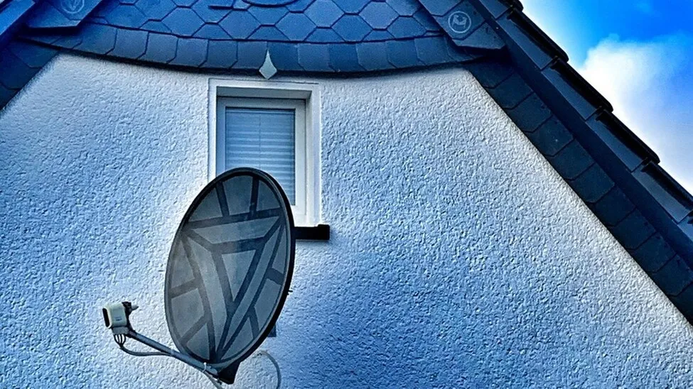 Nahaufnahme des oberen Teils eines Hauses. In der Mitte befindet sich eine Dachantenne, auf der ein Comic-Symbol zu sehen ist.