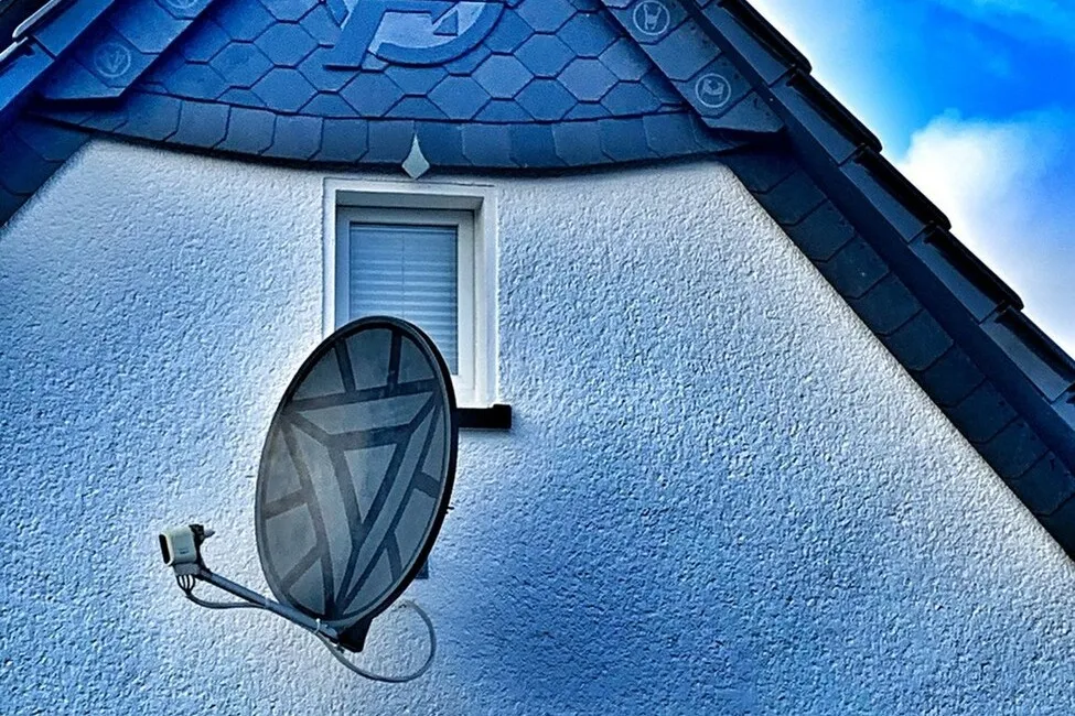 Nahaufnahme des oberen Teils eines Hauses. In der Mitte befindet sich eine Dachantenne, auf der ein Comic-Symbol zu sehen ist.