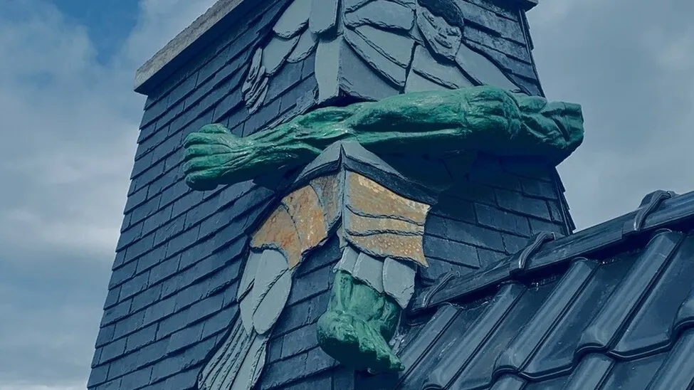 Eine in das Dach eines Hauses eingearbeitete Schieferkunst in Form des bekannten Hulk.