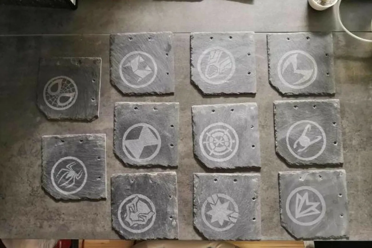Elf Steinplatten sind in dreier Reihen nebeneinander platziert. Darauf sind Comic Symbole zu sehen.