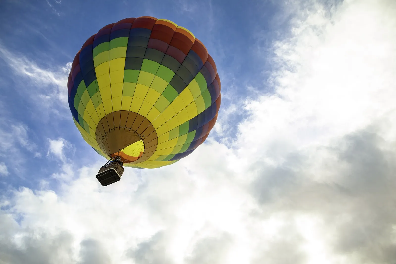 Aus der Froschperspektive: Ein bunter Heißluftballon steigt in den Himmel auf.